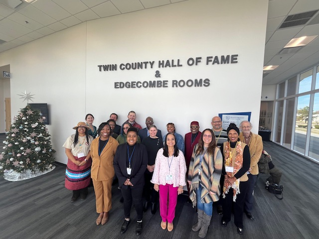 Group of 17 adults standing in front of a sign that says "Twin County Hall of Fame & Edgecombe Rooms."